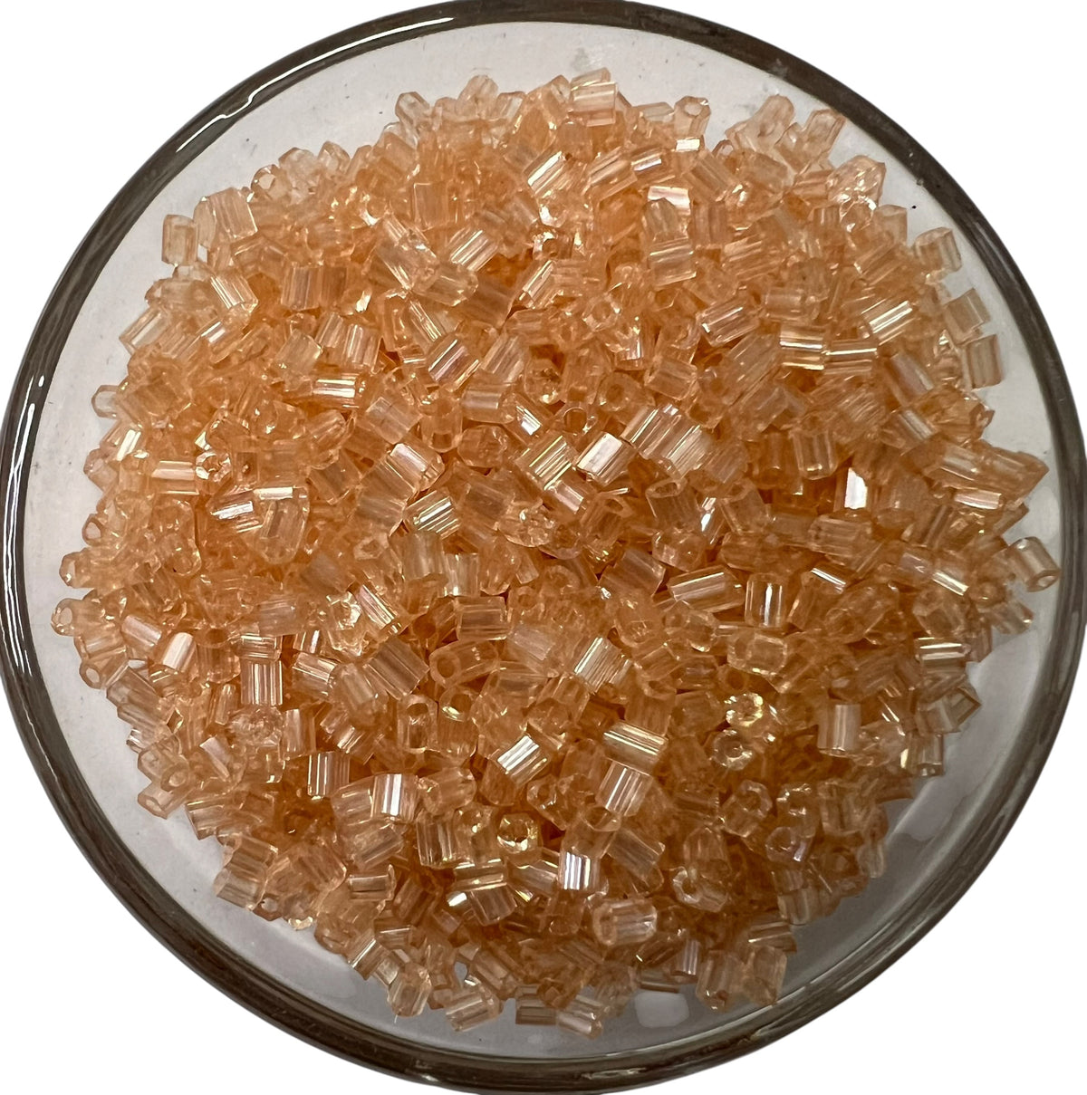 Loose peach cut glass beads for DIY jewelry making spread out on a clean white background.