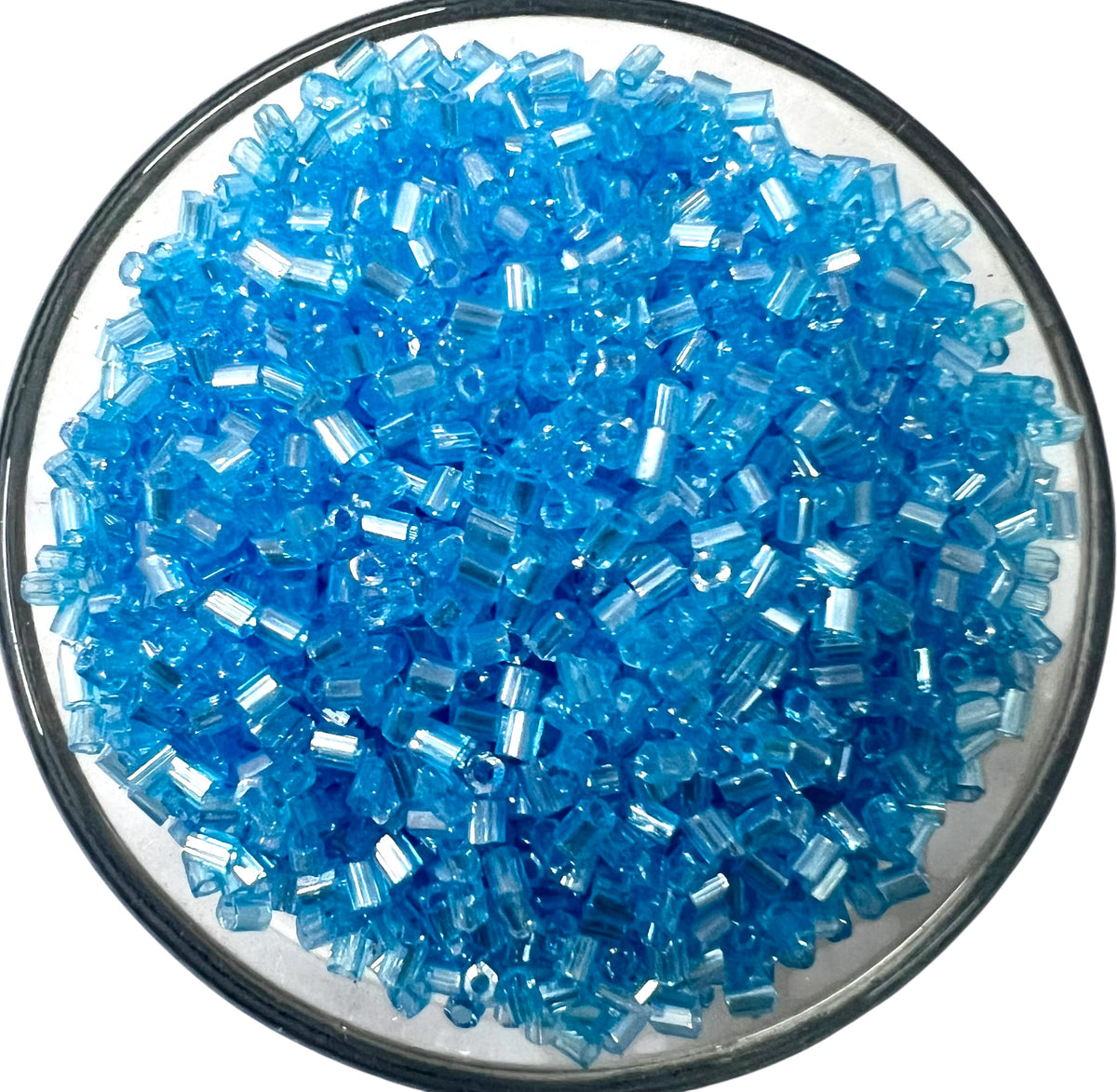 Loose sky-blue cut glass beads for DIY jewelry making spread out on a clean white background.